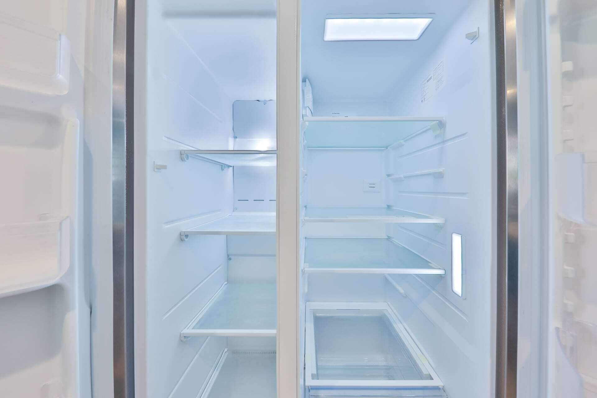 An empty interior of a modern refrigerator with multiple shelves and a built-in ice maker.