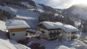 A snow-covered mountain area with buildings, parked cars, and a clear sky. - Cozy Holiday Apartment Near the ski Slope (Maria Alm am Steinernen Meer)