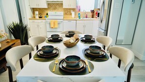 A dining table set with bowls, plates, and cutlery, surrounded by chairs. - Private Pool Paradise Near Hard Rock & Beach (Hollywood)