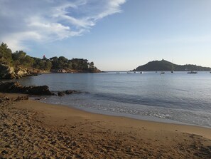 A beach with calm waters, boats, and a distant hill with a lighthouse. - 200 meters from the beach and restaurants, beautiful apartment for 6 people, air-conditioned, with a pool (Saint-Raphaël)