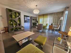 A modern living room with a sofa, ottoman, and a dining area with chairs and a table. - 200 meters from the beach and restaurants, beautiful apartment for 6 people, air-conditioned, with a pool (Saint-Raphaël)