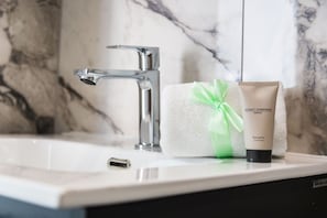 Ein Badezimmer mit Marmorwaschbecken, einem Handtuch und einer Balsamo Conditioner-Flasche.