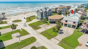 Vista aérea de una zona residencial costera con casas, una playa y cielo despejado.