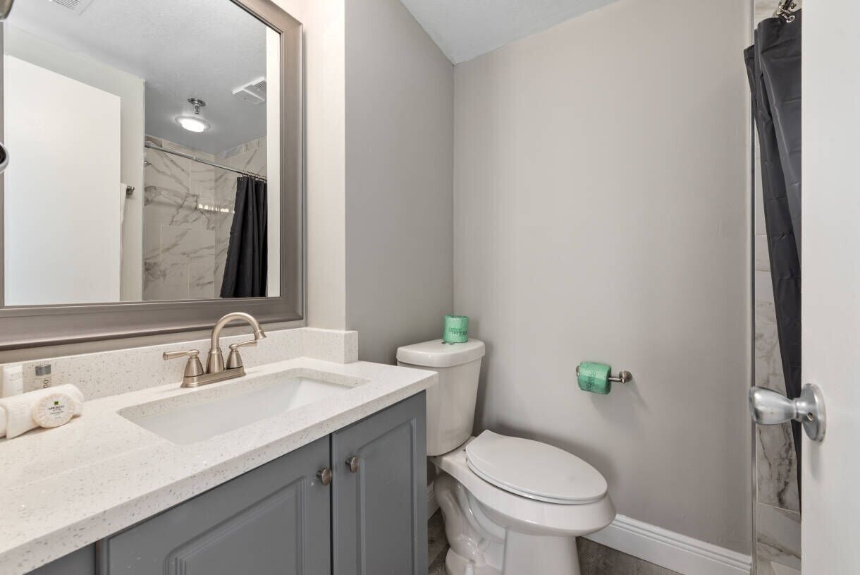 A bathroom with a sink, toilet, and shower area.