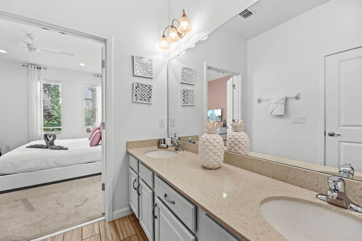 A modern bathroom with a large mirror, two sinks, and decorative wall art.