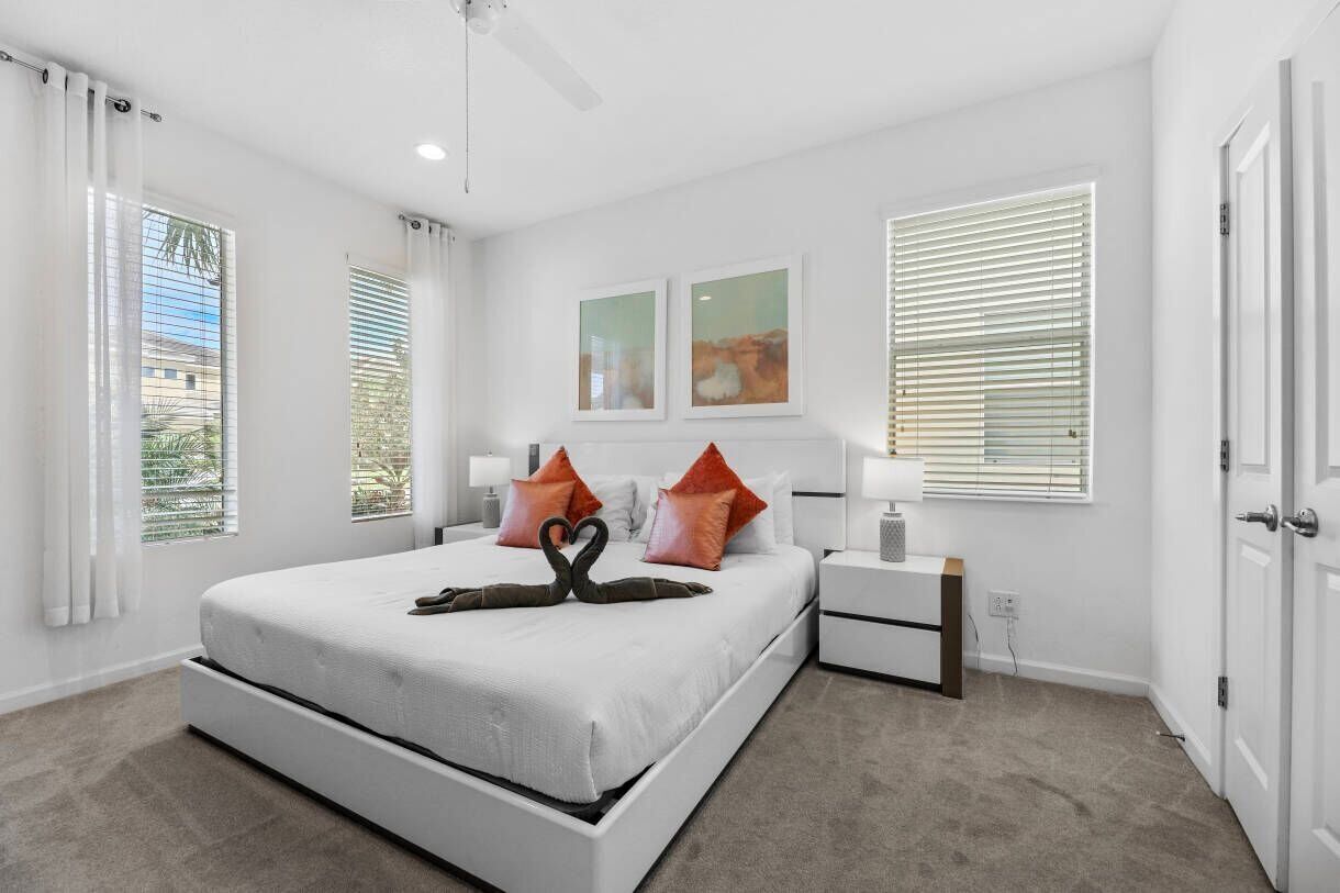 A bedroom with a bed, nightstands, a ceiling fan, and artwork on the wall.
