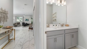 A modern bathroom with a large mirror, vanity, and a marble floor. - Storey Lake Home Pool 15min to Disney (Kissimmee)
