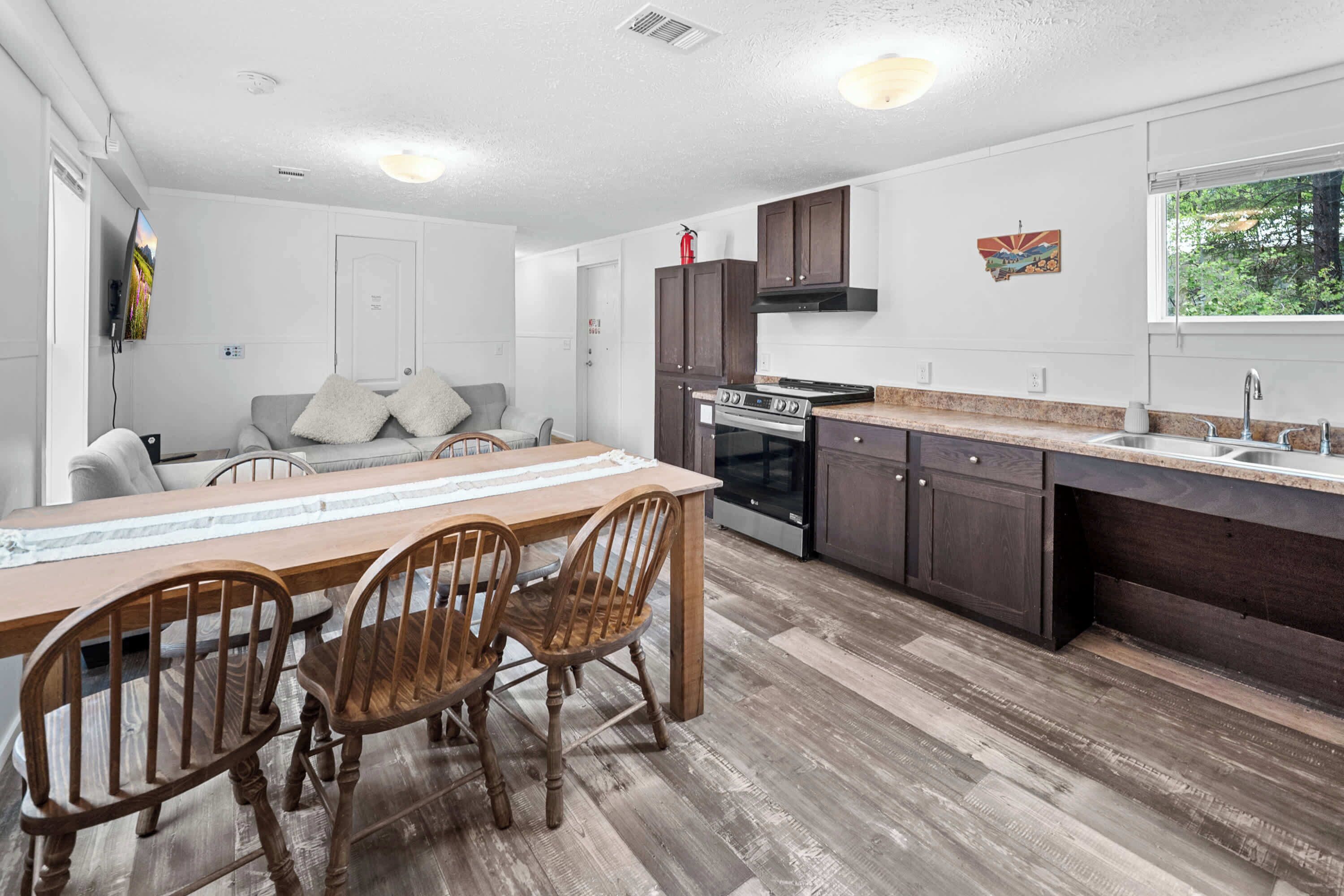 A modern kitchen with wooden cabinets, a built-in oven, and a large dining table with chairs.