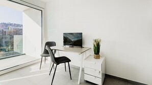 A modern office space with a desk, chair, TV, and a potted plant. - {Suite 603} Gym, Business Room, Modern, Relax (Lugano)