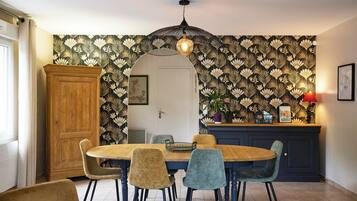 Un coin repas comprenant une table ronde en bois, quatre chaises, un buffet et un papier peint à motifs.