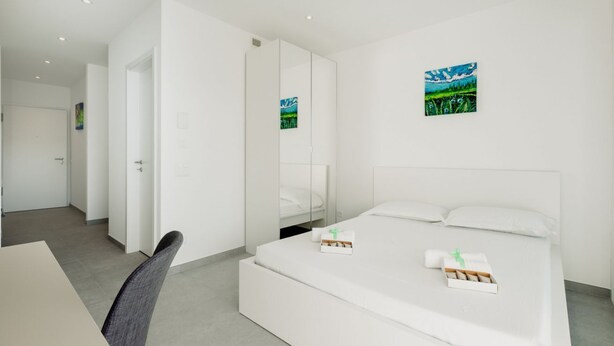 Una camera d'hotel moderna con un letto, una scrivania e una sedia.