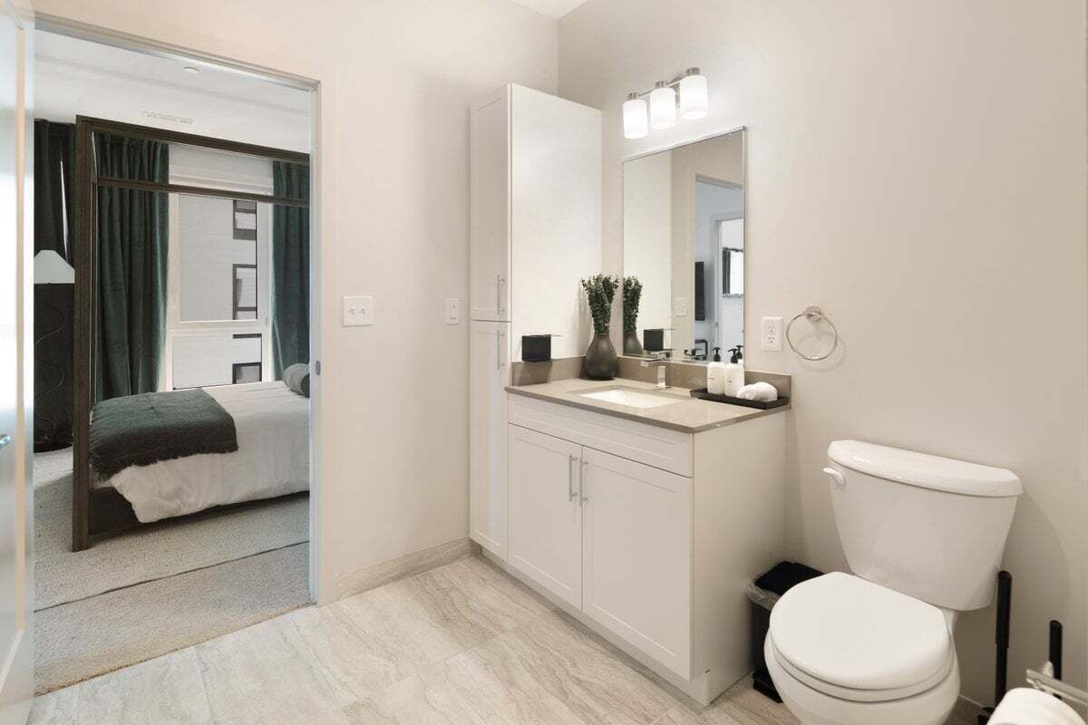 A modern bathroom with a toilet, sink, and mirror.