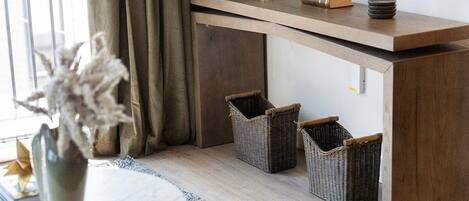 A modern living room with a wooden console table, wicker baskets, a vase with dried flowers, and a round table.