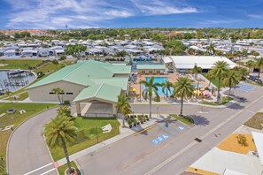 A hotel with a swimming pool, a covered parking area, and a view of the surrounding neighborhood.