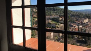 Une fenêtre donnant sur une ville, des bâtiments et de la verdure.