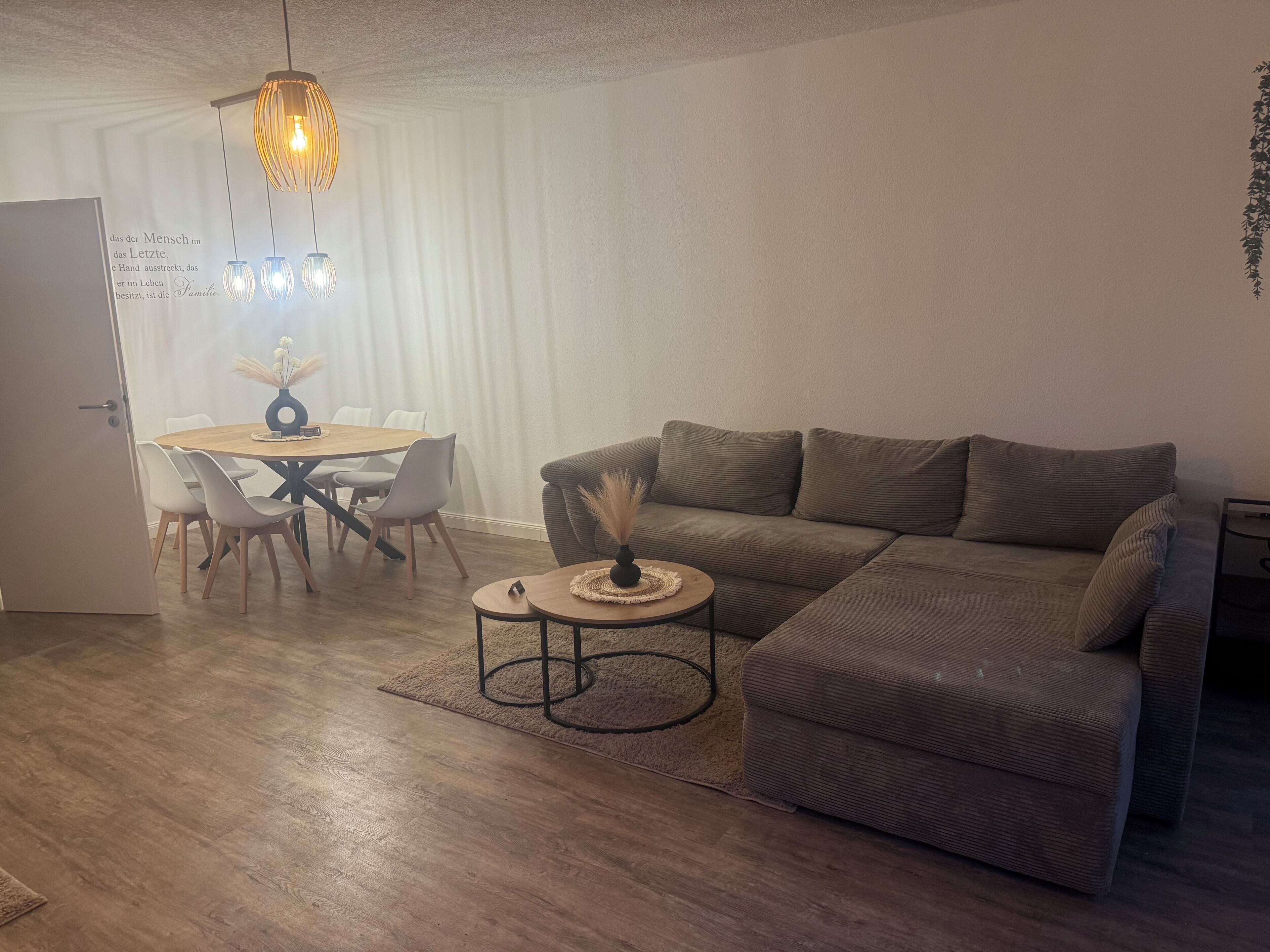Ein Wohnzimmer mit einer Couch, einem Couchtisch, einem Esstisch mit Stühlen und einer Pendelleuchte.