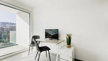 Un espacio de oficina moderno con escritorio, silla, televisor y una planta en maceta.