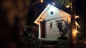 A small brick house with a pitched roof, a visible door, and a window.