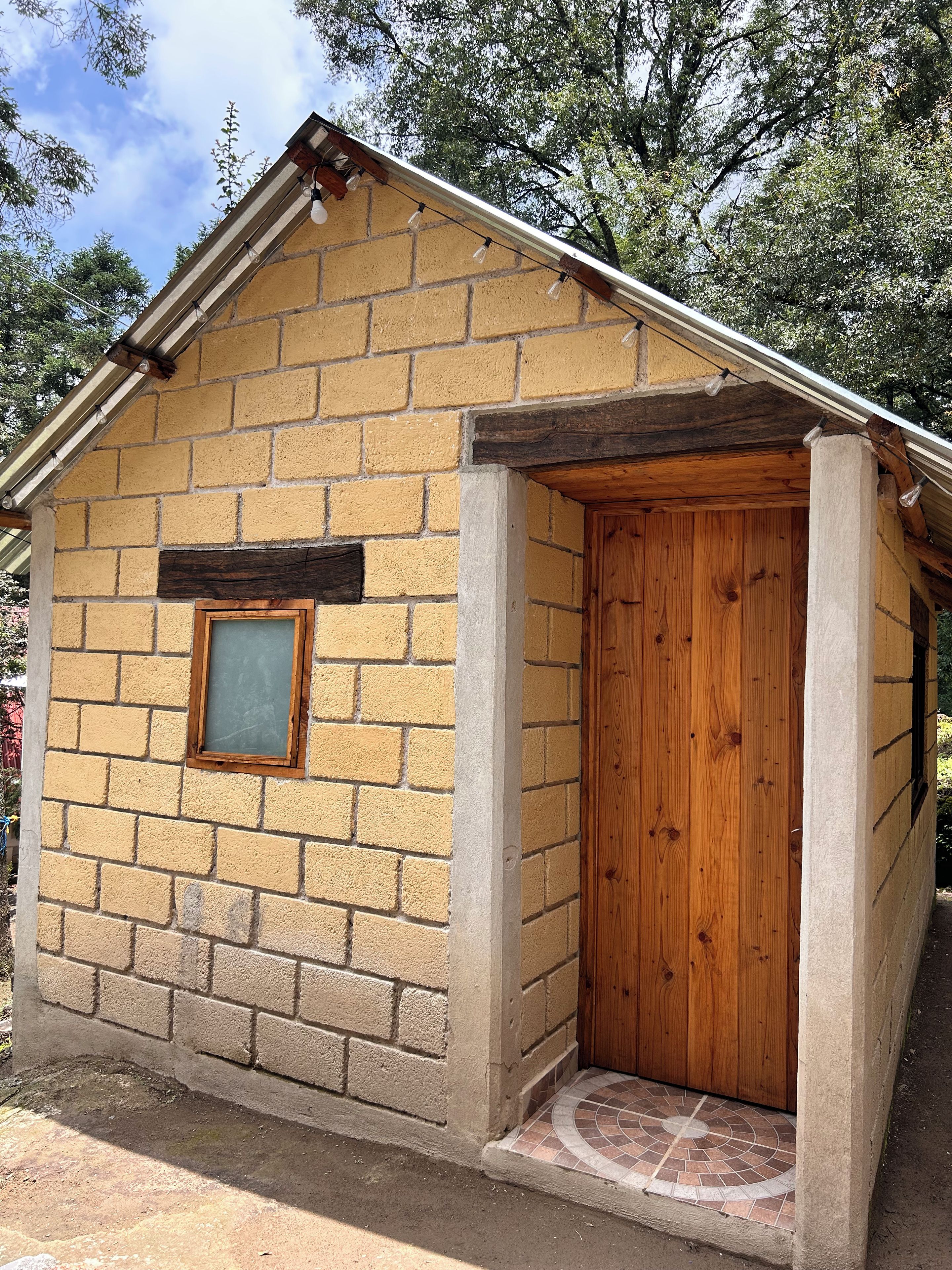 Un pequeño edificio de ladrillo con una puerta de madera y una ventana.