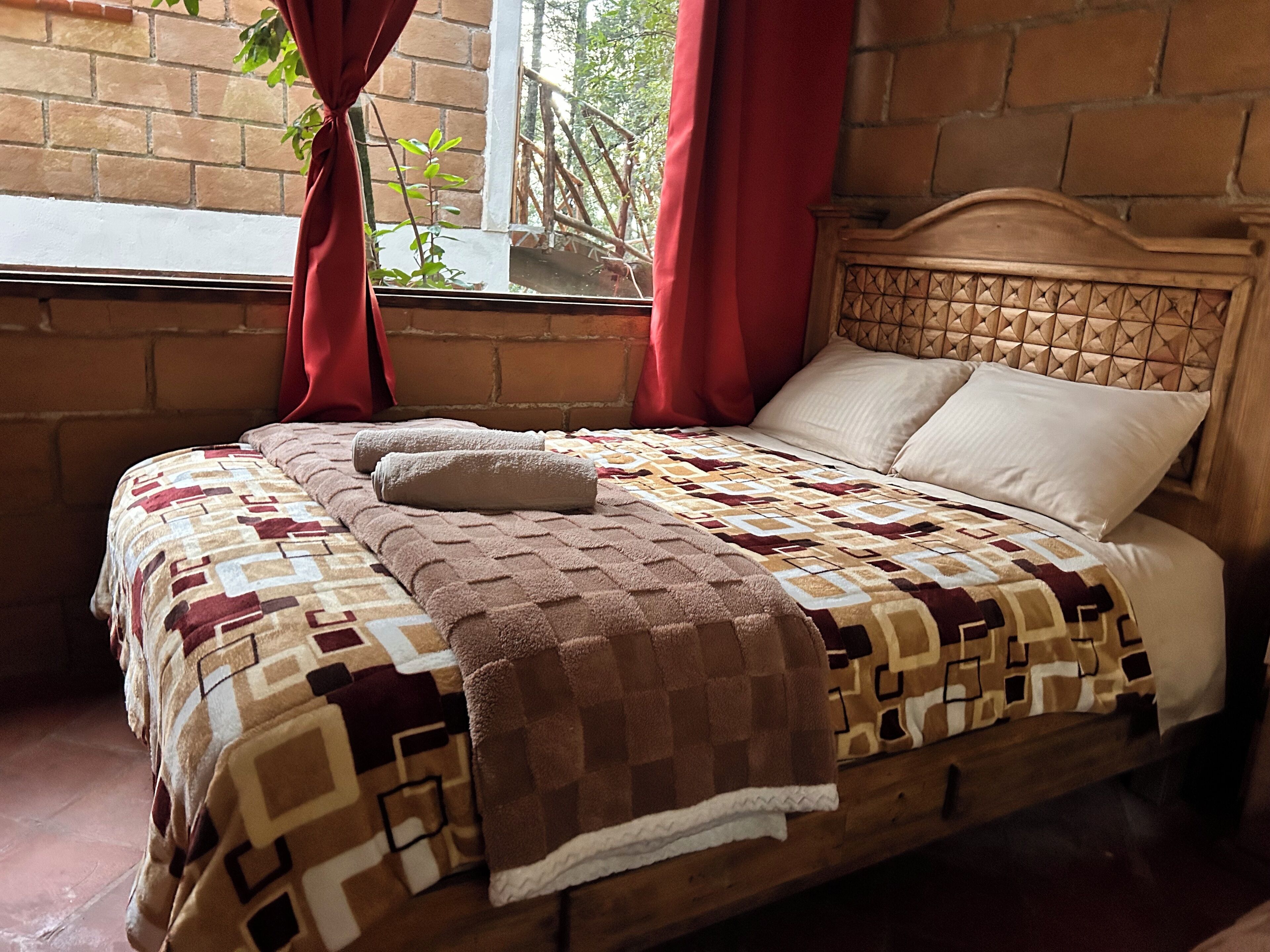 A bed with a patterned bedspread, a pillow, and a blanket.