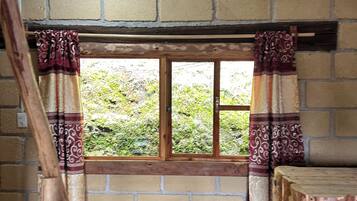 Una habitación con ventana, vigas de madera y pared de ladrillo.