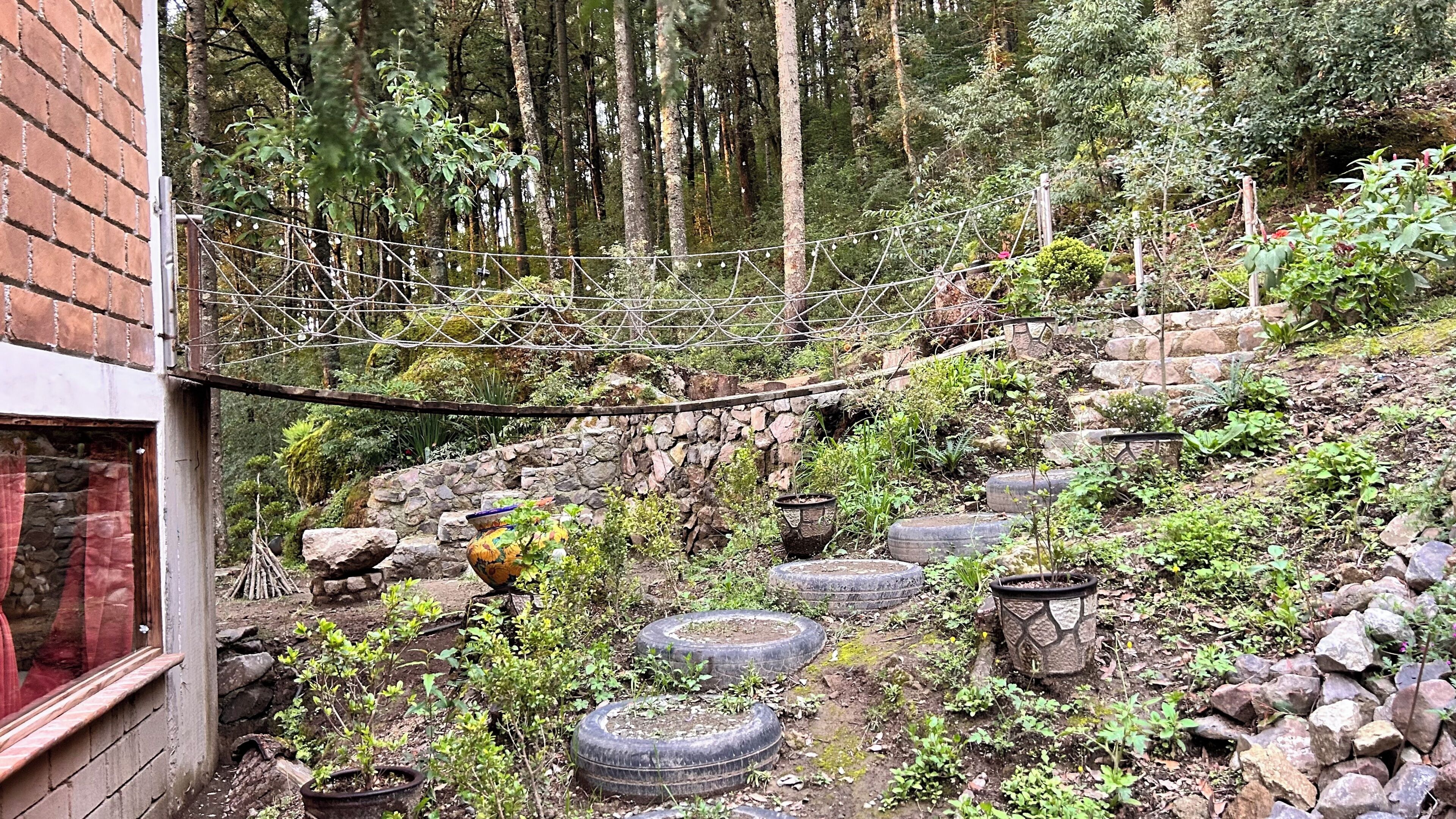 A rustic outdoor area with a wooden fence, stone walls, and tire planters.