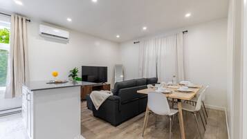 Una sala de estar moderna con un sofá, mesa de comedor y televisor.