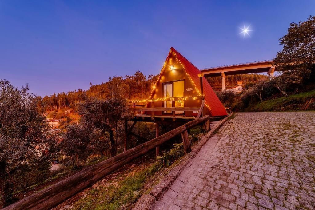A cabin with a wooden deck, a small porch, and a starry sky.