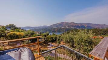 Une terrasse en bois offrant une vue sur un lac et des montagnes.