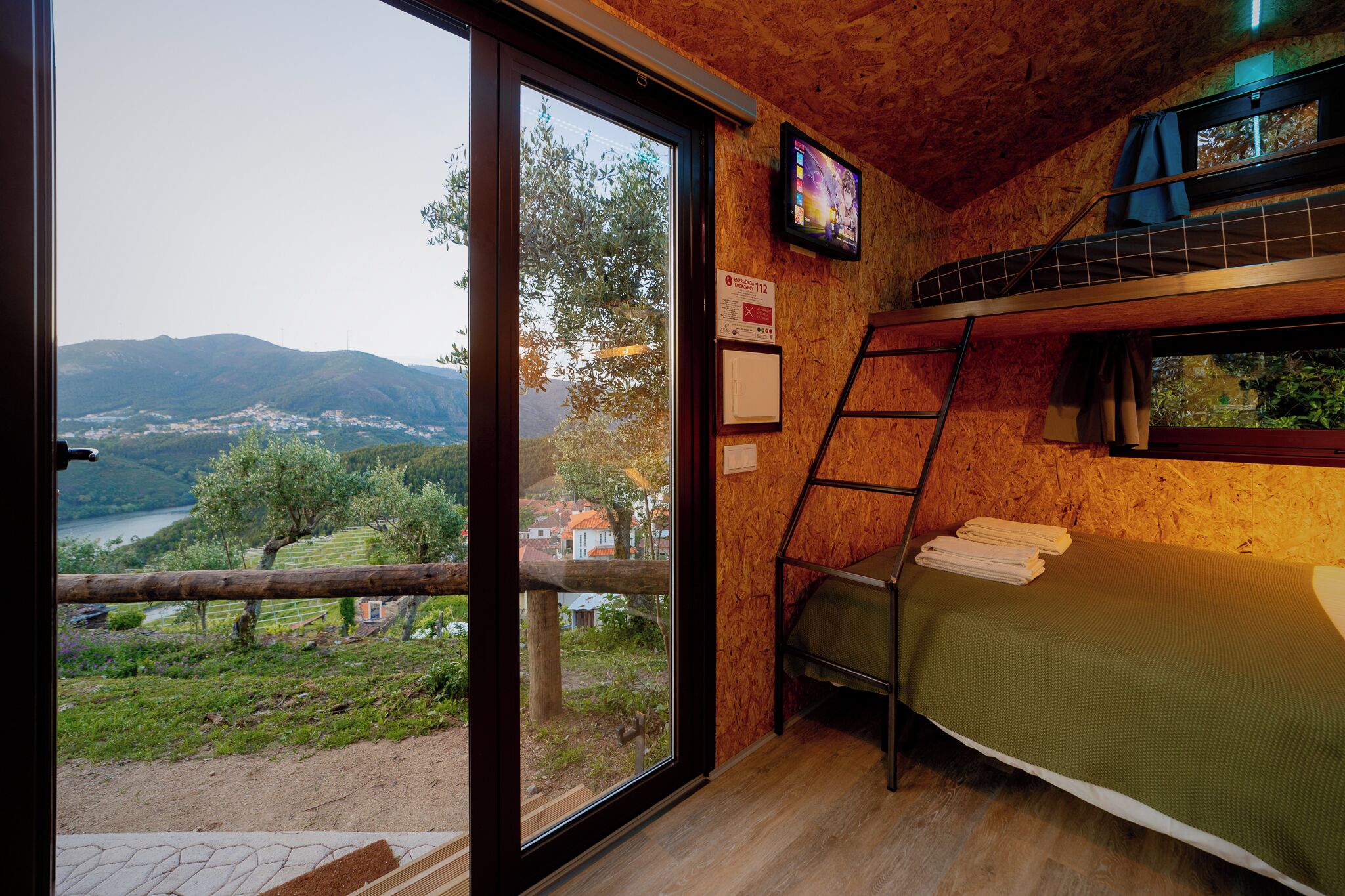 Ein Zimmer mit Etagenbett, Fernseher und Blick auf ein Tal.