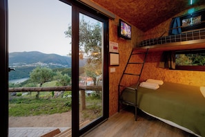 A room with a bunk bed, a television, and a view of a valley. - Arrabia GUEST HOUSES GLAMPING (Raiva)
