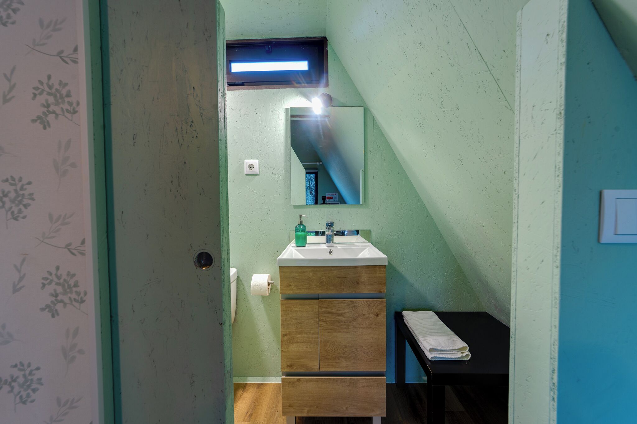 A bathroom with a wooden vanity, a mirror, a sink, and a towel rack.
