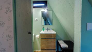 A bathroom with a wooden vanity, a mirror, a sink, and a towel rack.