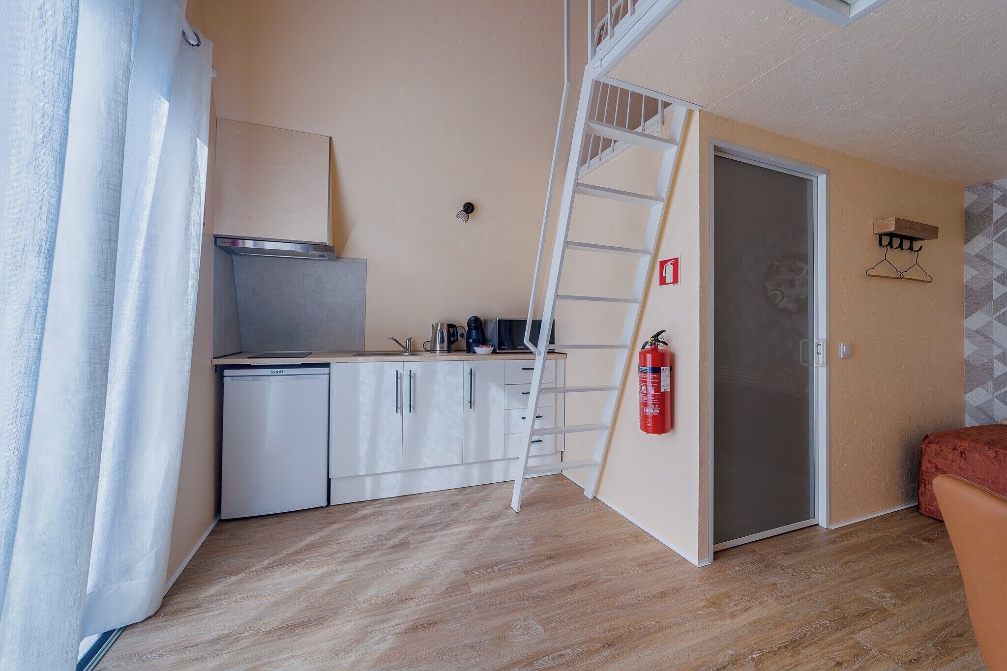 A compact kitchen with a white refrigerator, a stove, and a coffee maker on the counter.