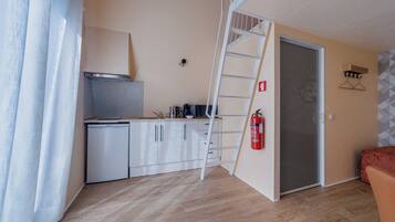 A compact kitchen with a white refrigerator, a stove, and a coffee maker on the counter.