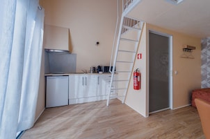 Una cocina compacta con un refrigerador blanco, una estufa y una cafetera sobre la encimera.