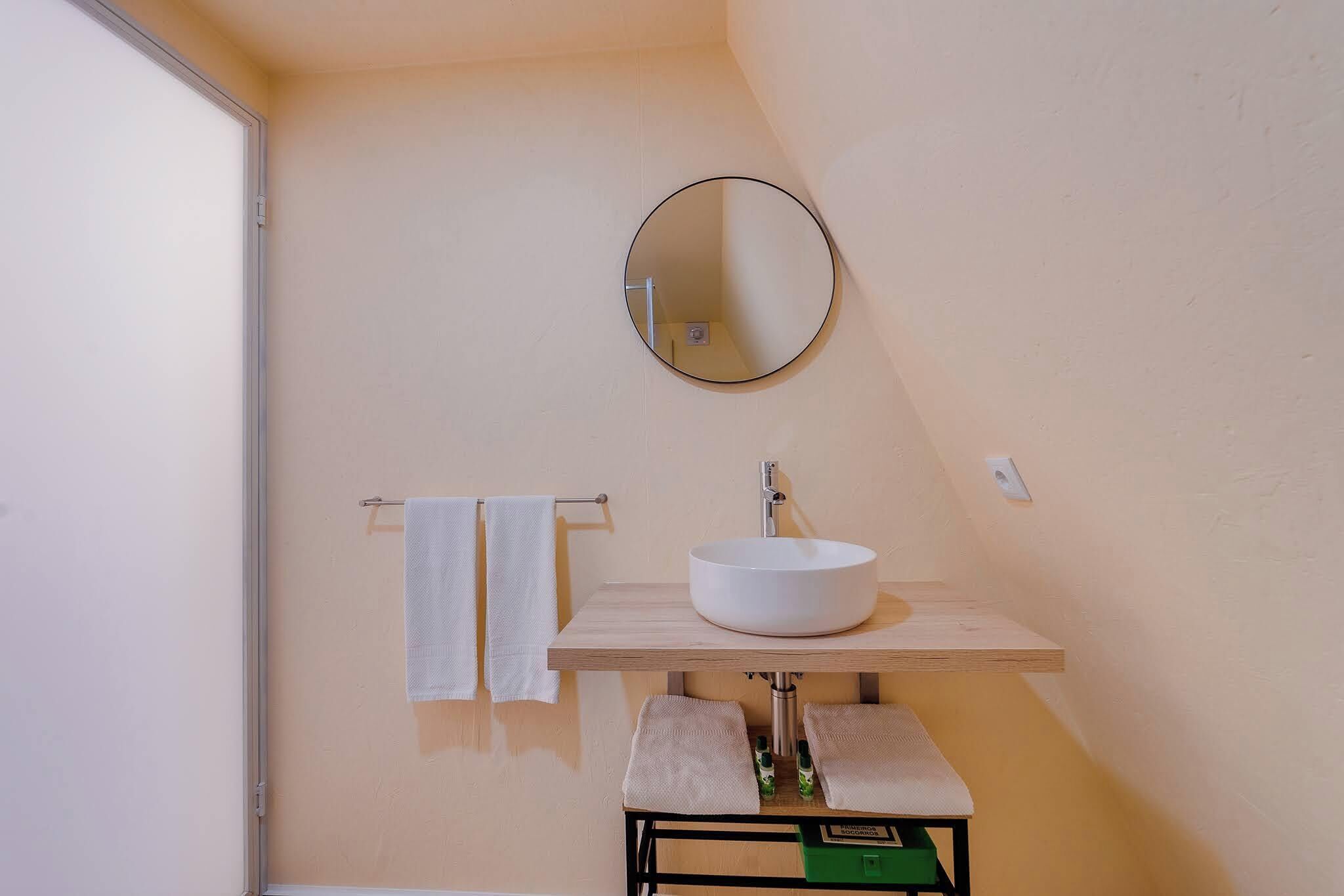 A bathroom with a white sink, a mirror, and two towels on a rack.