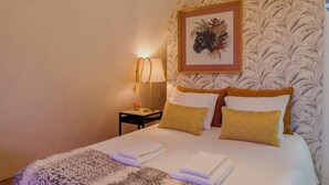 A hotel room with a bed, a nightstand with a lamp, and a framed picture on the wall.