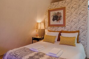 Una habitación de hotel con una cama, una mesita de noche con lámpara y un cuadro en la pared.