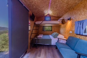 Una habitación compacta con una cama individual, un sofá, un televisor y una ventana con vistas al exterior.