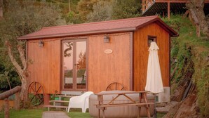 A wooden cabin with a glass door, a bench, a table, and an umbrella.