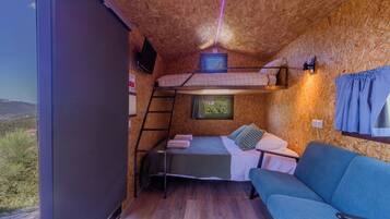Habitación compacta con literas, un sofá, un televisor y ventana con vistas al exterior.