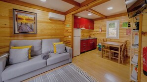 A cozy cabin interior with a sofa, a dining table, and a kitchen area.