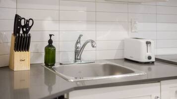 A kitchen with a sink, a toaster, and a knife block.