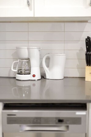 A kitchen with a coffee maker, a mug, and a knife block on the counter.