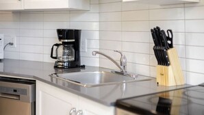 Uma cozinha com cafeteira, pia e porta-facas.