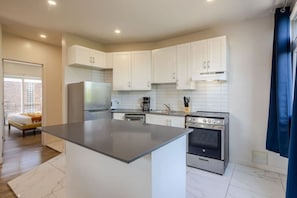 A modern kitchen with white cabinets, a central island, a stove, and a dishwasher.
