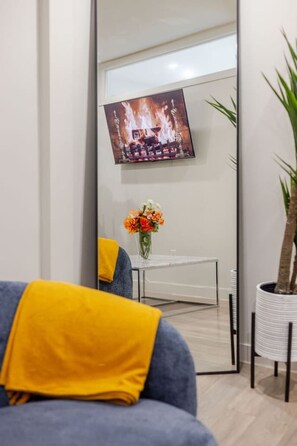 A modern living room with a sofa, a coffee table, a TV mounted on a wall, and a potted plant. - Modern Apartment | Downtown Montréal (Montreal)