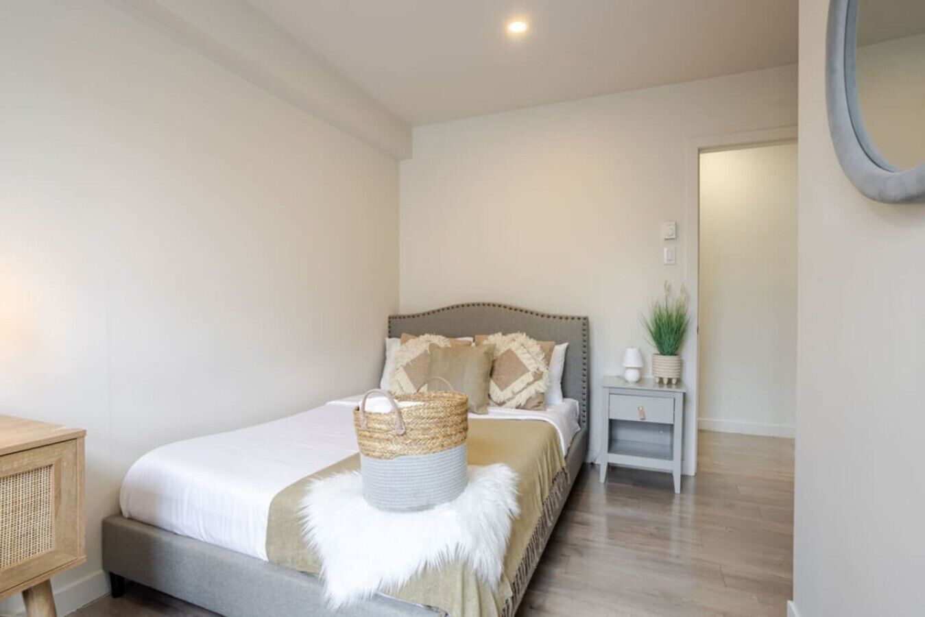 Een keurig opgemaakt slaapkamer met een bed, nachtkastje en een kleine plant in pot.