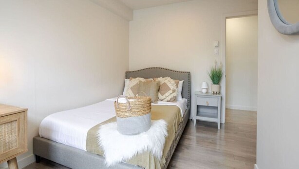 Quarto bem arrumado com cama, mesa de cabeceira e uma pequena planta em vaso.